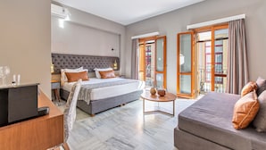 Une chambre d’hôtel avec un lit, un canapé, un bureau avec un ordinateur et une petite table.
