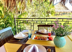 A dining table set with plates, a glass of iced drink, and a vase of flowers.