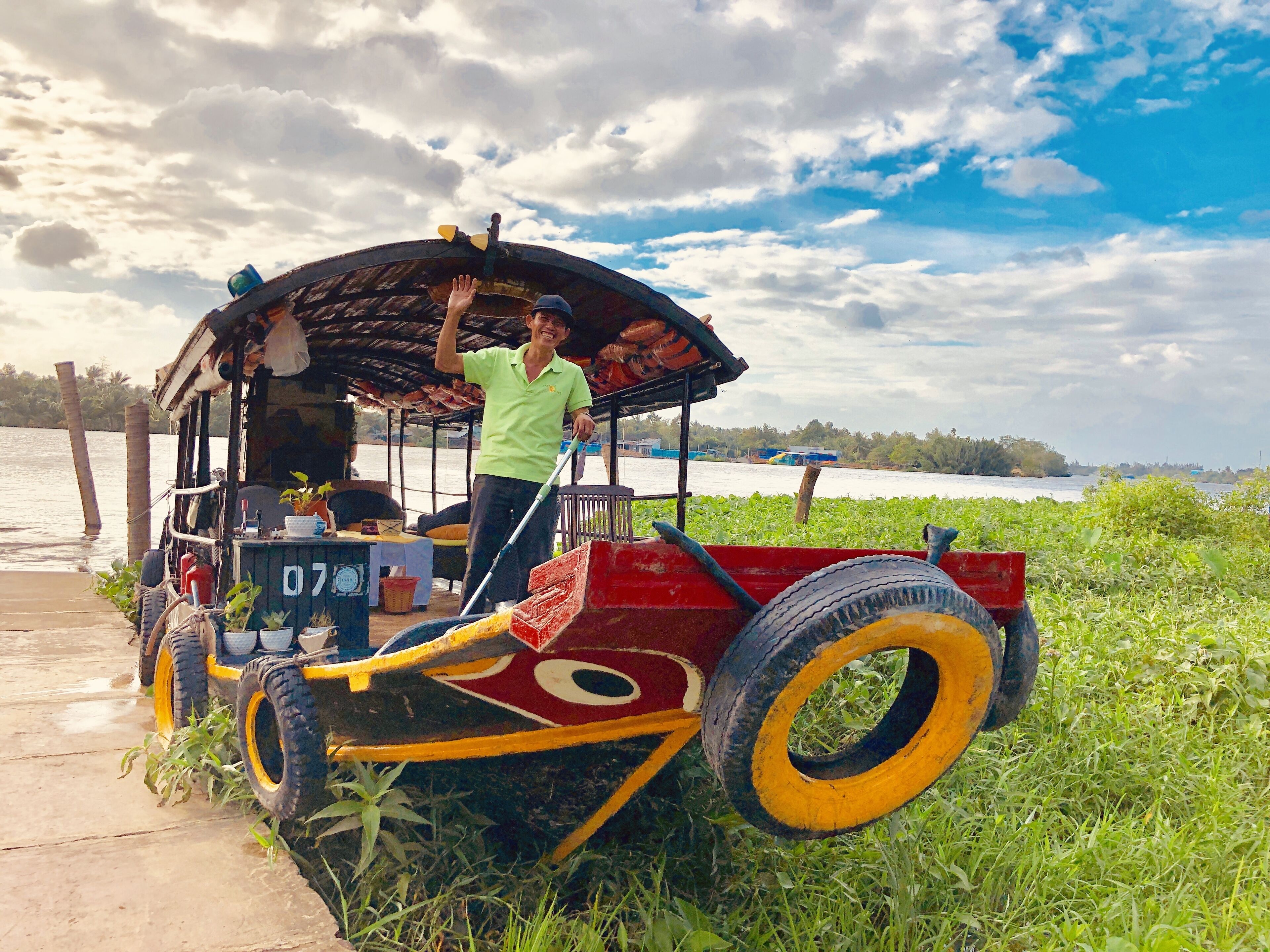 A colorful, rustic boat with a person standing on the deck.