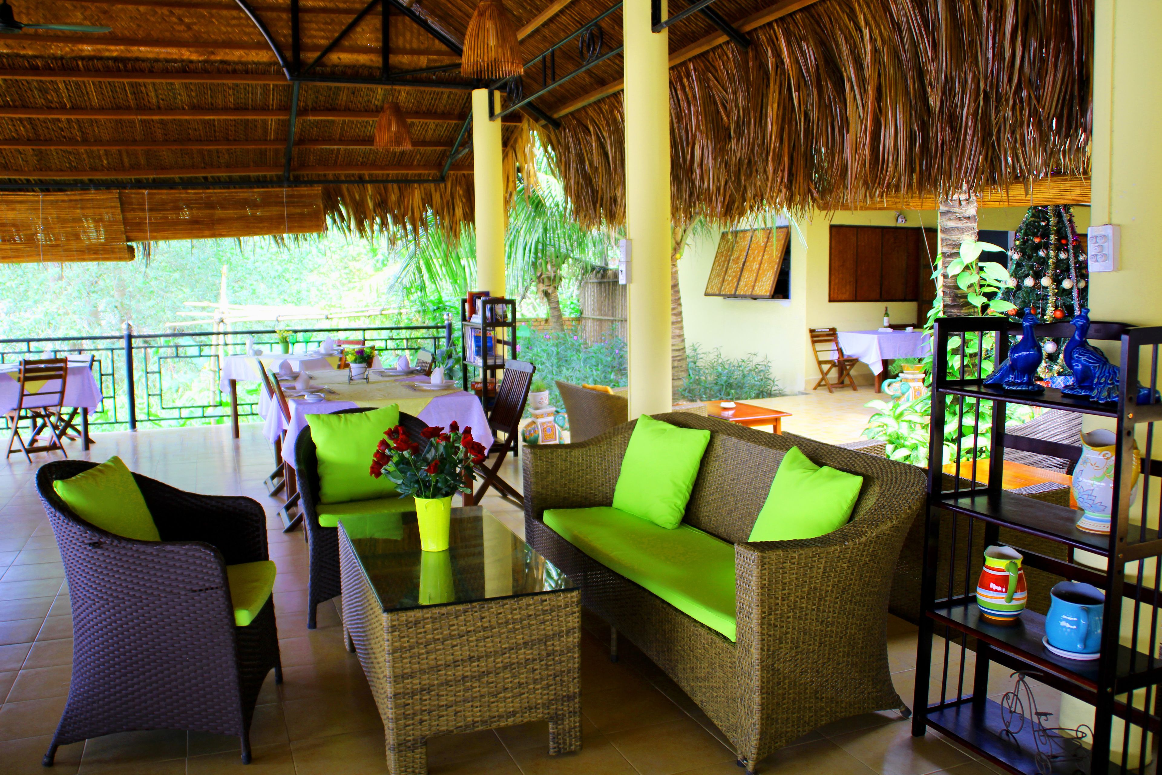 A covered outdoor seating area with wicker furniture, a glass-top table, and a Christmas tree.