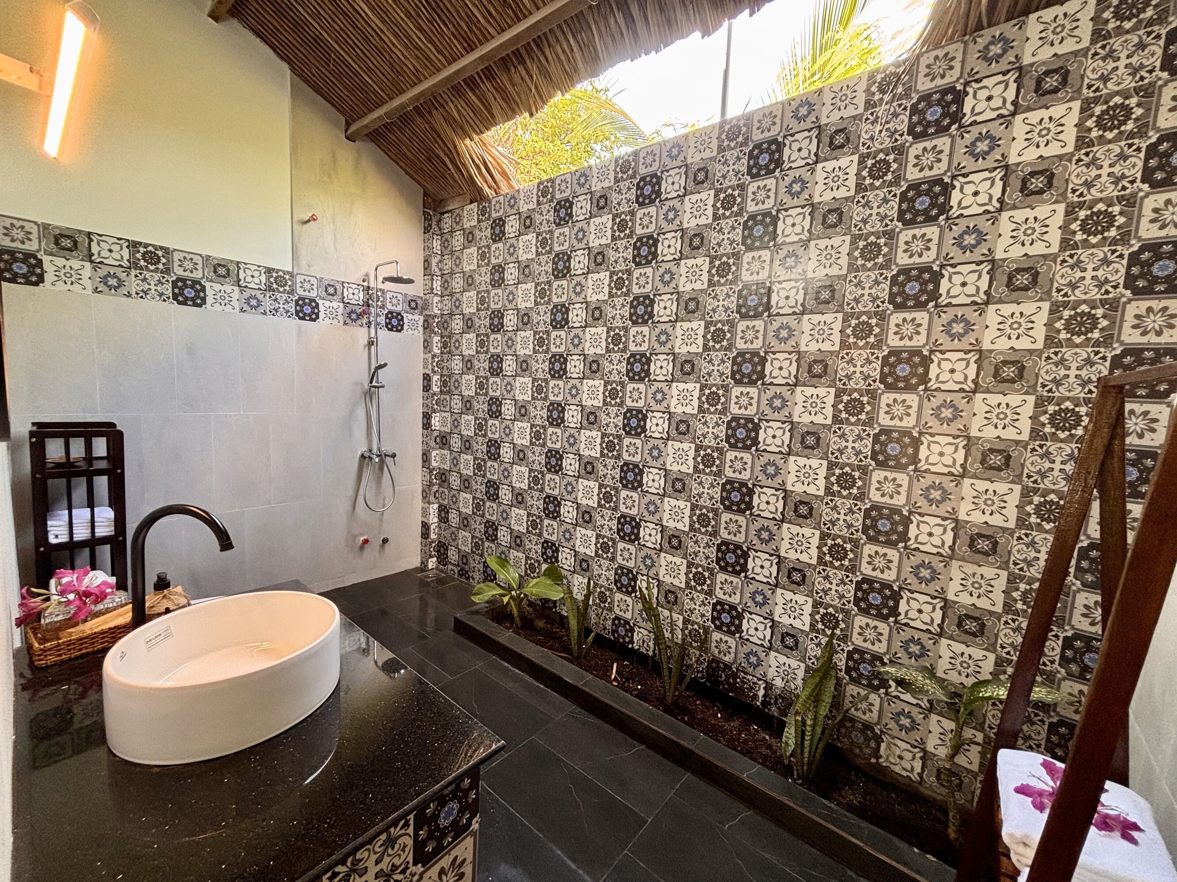 Casa de banho com parede de chuveiro revestida em azulejo, uma pia e um chuveiro.