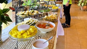 A buffet setup with various food items and a person serving.