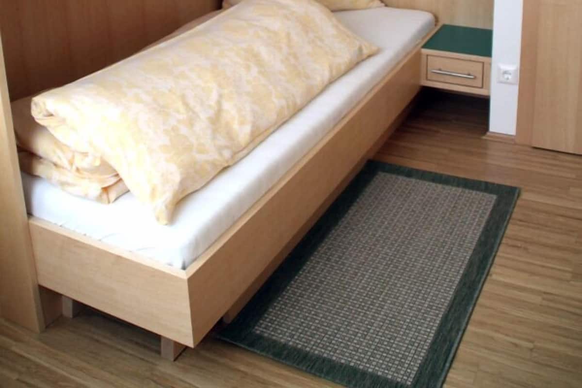 Ein kleines Zimmer mit Bett, Nachttisch und Kleiderschrank.