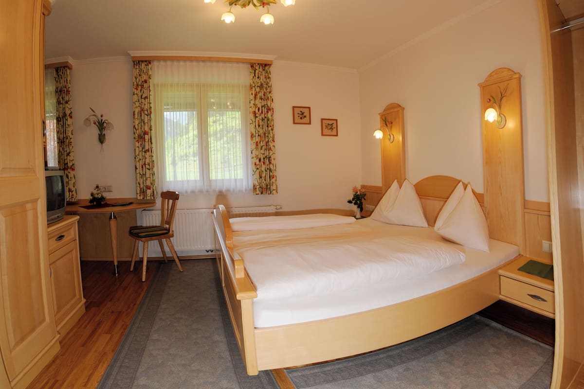 Ein Hotelzimmer mit einem hölzernen Bett, einem Schreibtisch, einem Stuhl und einer Heizung.