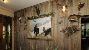 Pared con paneles de madera, cráneos de animales montados y un cuadro enmarcado con dos ciervos.