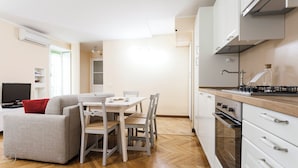 A compact living space with a dining area, kitchenette, and a television. - Italianway   - Lazzaro Palazzi (Milan)