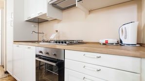 A modern kitchen with a stainless steel stove, a built-in oven, white cabinetry, and a wooden countertop. - Italianway   - Lazzaro Palazzi (Milan)