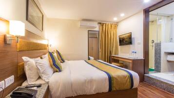 Een hotelkamer met een bed, nachtkastje, lamp, telefoon en een badkamer met douche en wastafel.