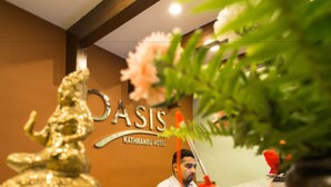 Mostrador de recepción en el Hotel Kathmandu con una estatua dorada, una recepcionista y un cartel.