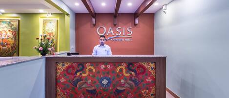 A reception desk with a floral design and the name "OASIS" above it.