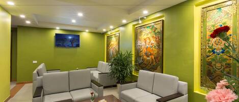 A modern living room with green walls, two sofas, a coffee table, and decorative paintings.