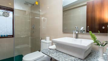 Un baño moderno con cabina de ducha de vidrio, lavamanos blanco y retrete.