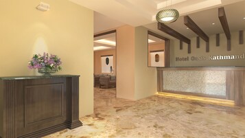 Zona de recepción con suelo de mármol, mostrador de madera oscura y un cartel en la pared que dice "Hotel Oasis Kathmandu".