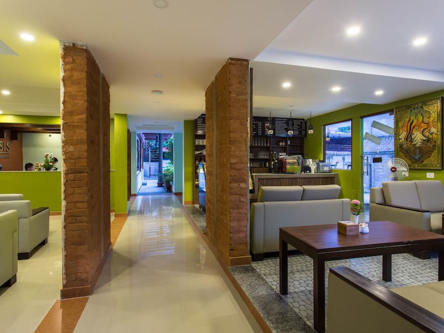 A hotel lobby with a central seating area, a reception desk, and a bar area.