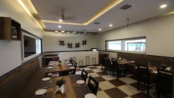 A restaurant with a checkered floor, wooden tables, and chairs. There are ceiling fans and recessed lighting.