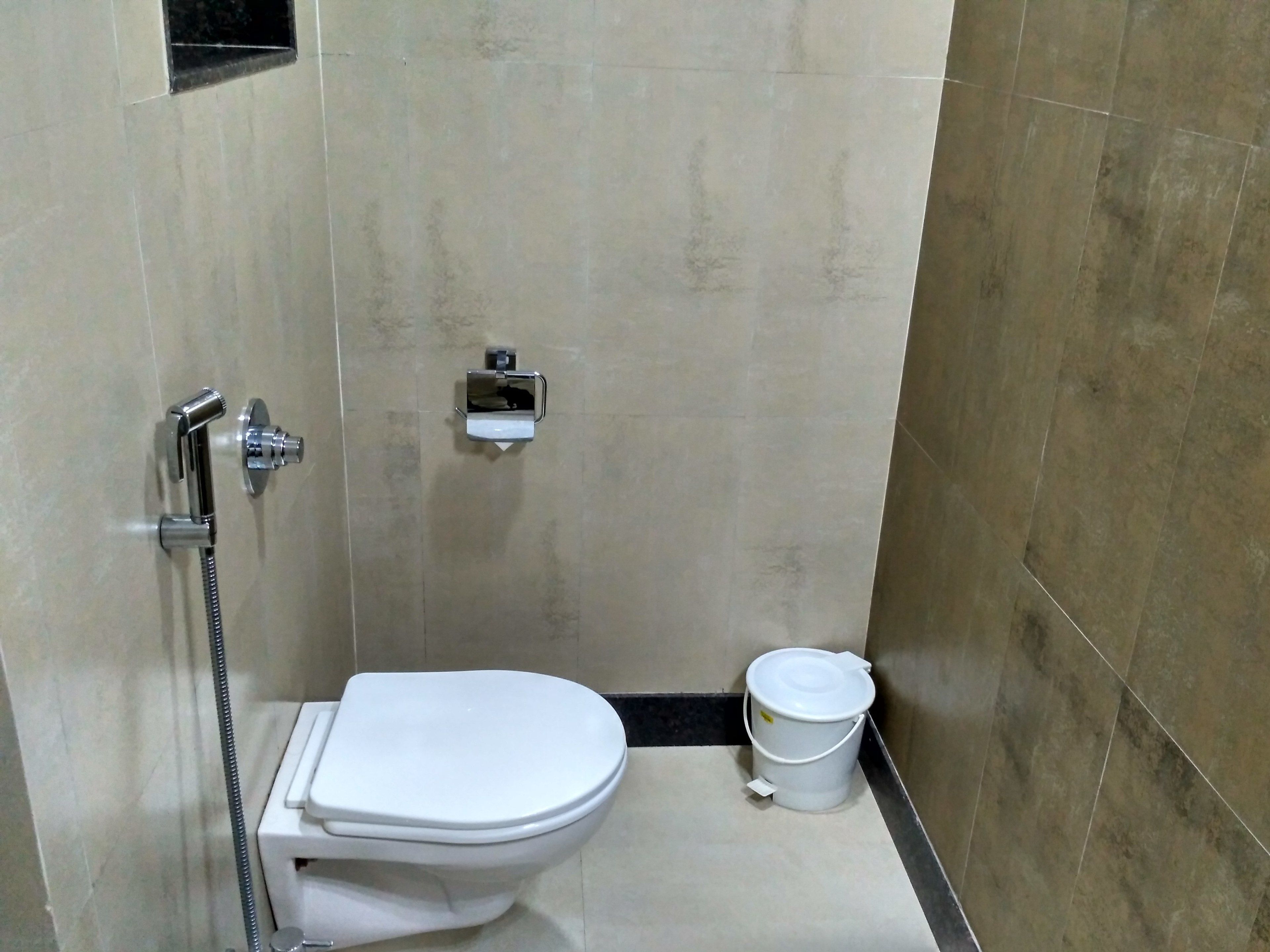 Et lille, moderne badeværelse med toilet, bruser og toiletpapirholder.