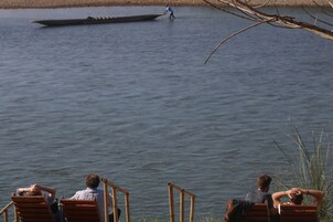 Vista del lago con una fila de sillas de madera mirando hacia el agua.