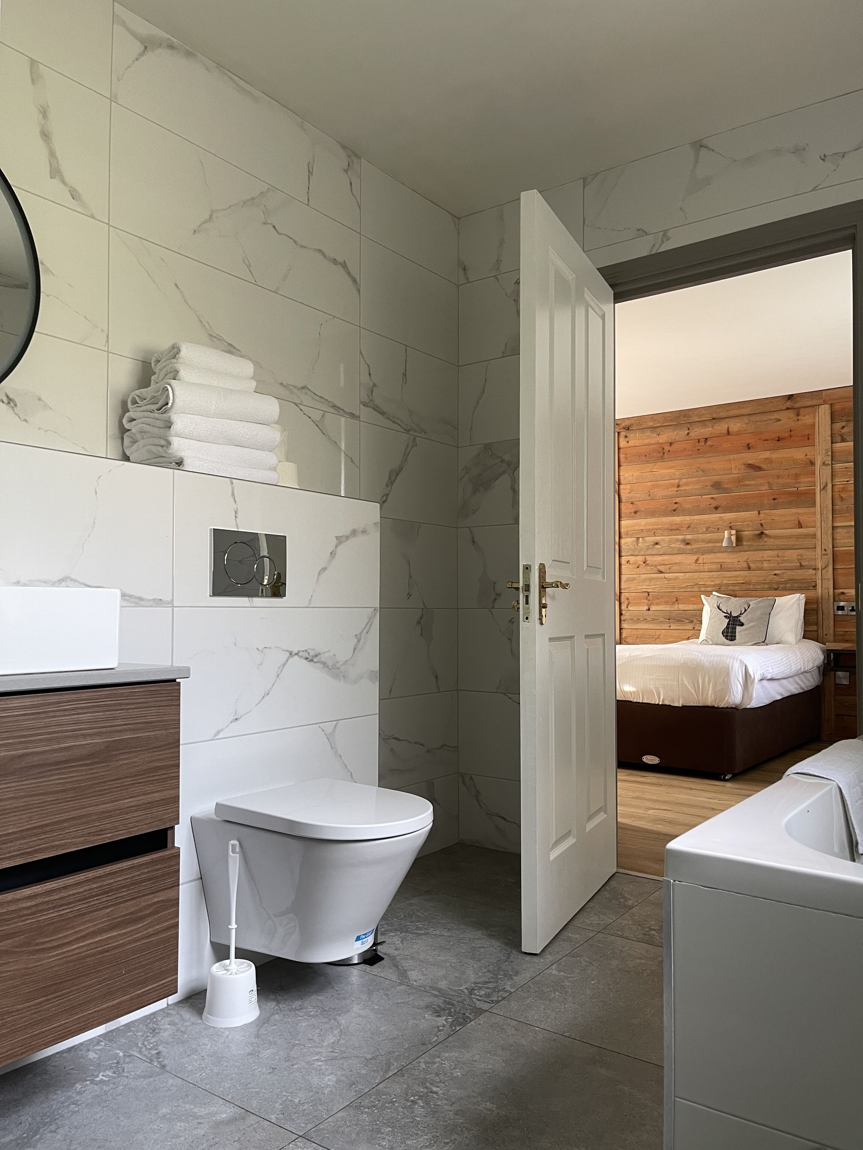 A modern bathroom with a toilet, bidet, and a wooden vanity.