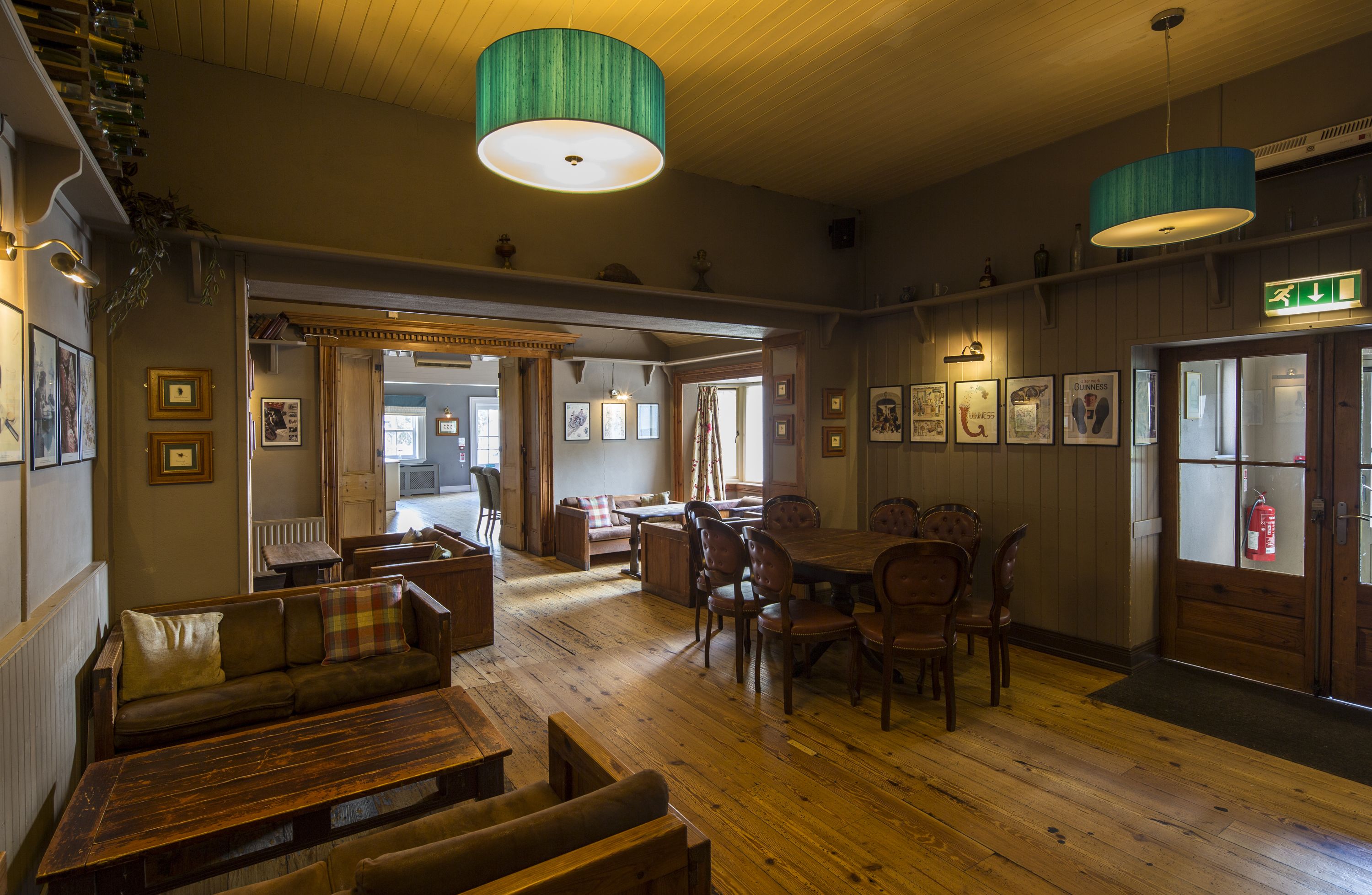 A cozy room with wooden floors, a sofa, a dining table with chairs, and a fireplace.