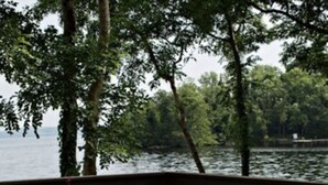 A wooden deck with a picnic table set for breakfast, overlooking a lake. - Lusty Beg Island (Enniskillen)