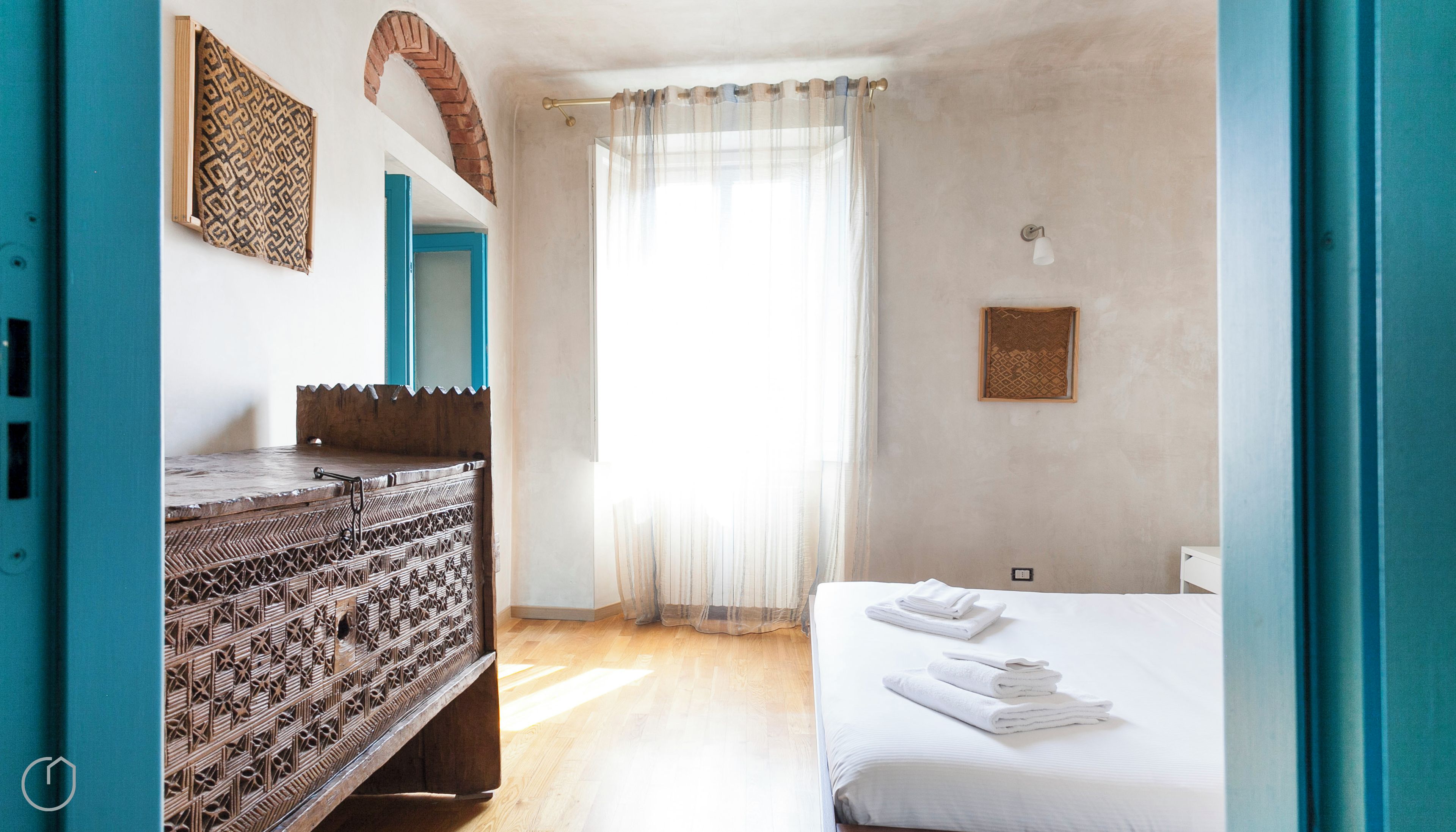 A bedroom with a bed, a dresser, a mirror, and a window with curtains.