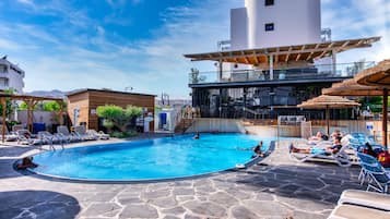Una piscina al aire libre, sillones reclinables de piscina
