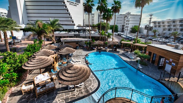 Ein Hotel mit Swimmingpool, Liegestühlen und Palmen.
