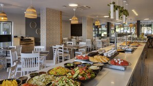 Ein Buffet mit verschiedenen Speisen und weißen Stühlen, die um Tische angeordnet sind.