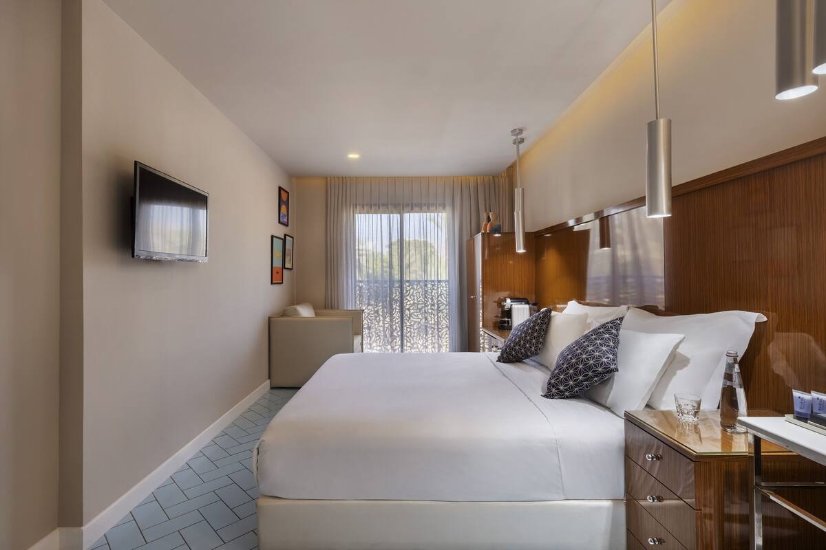 Une chambre d’hôtel avec un grand lit, une table de chevet et un téléviseur fixé au mur.
