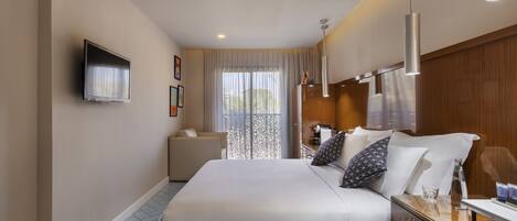 A hotel room with a large bed, bedside table, and a TV mounted on the wall.
