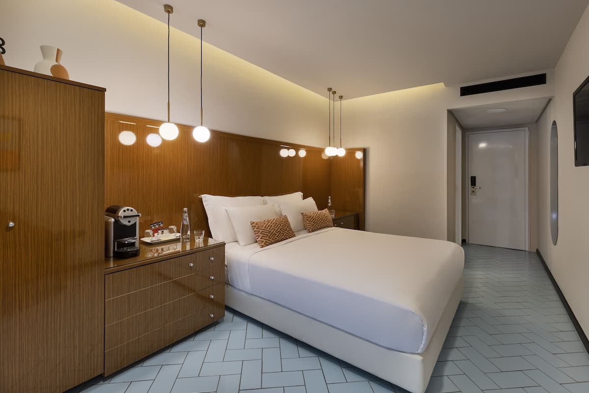 Une chambre moderne avec un grand lit, une armoire en bois, des tables de chevet et une machine à café.
