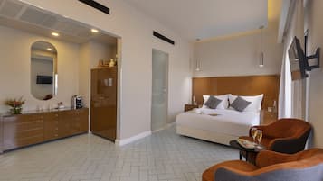 Ein modernes Hotelzimmer mit einem großen Bett, einem Holzschrank, einem kleinen Tisch mit Getränken und einer Sitzecke.