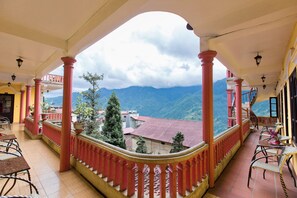 A balcony with red columns, a staircase, and a view of mountains. - SapaAubergeDangtrung Hotel (Sa Pa)