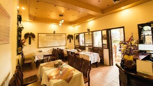 A restaurant interior with multiple tables and chairs, a large menu board, and decorative wall elements. - SapaAubergeDangtrung Hotel (Sa Pa)