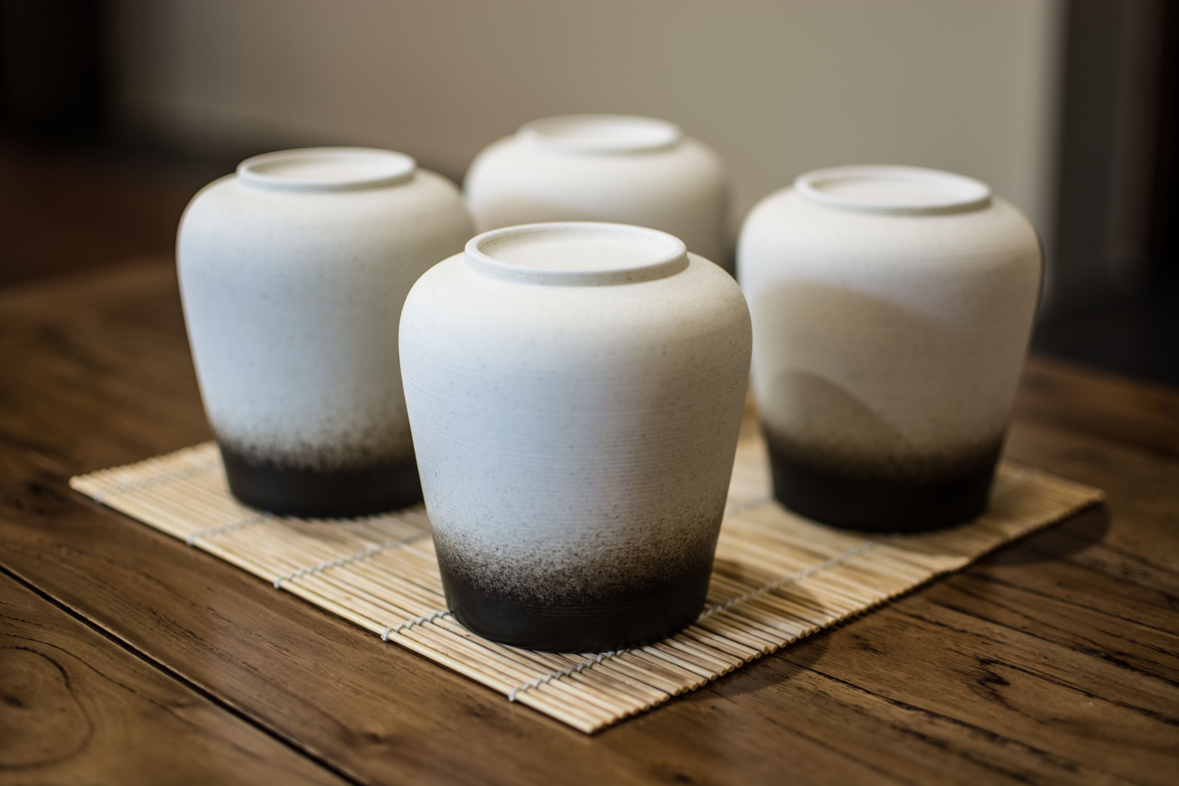 Four ceramic vases with a gradient design on a wooden table.