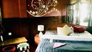 Une chambre à coucher comprenant un lit, une table de chevet, une lampe, un mur décoratif et une fenêtre avec des rideaux.