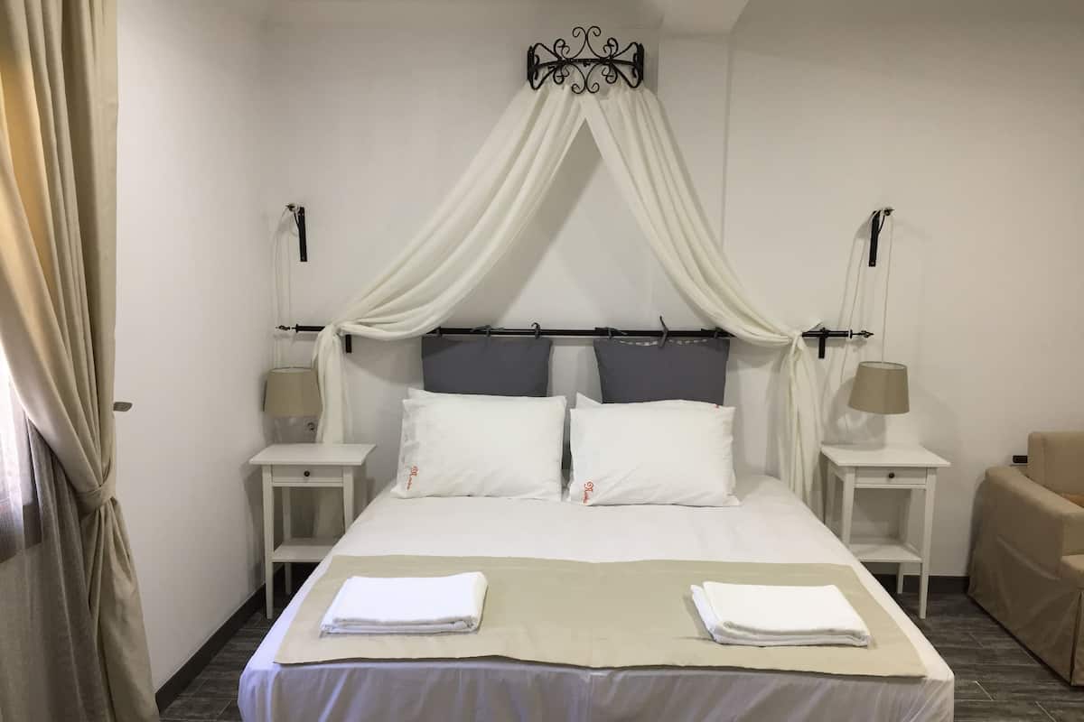 Une chambre à coucher bien aménagée, avec un lit à baldaquin, deux tables de chevet et un fauteuil.