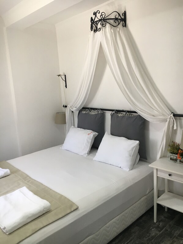 A neatly made bed with white linens, two pillows, and a beige throw blanket. - Nova Citrus Hotel (Seferihisar)