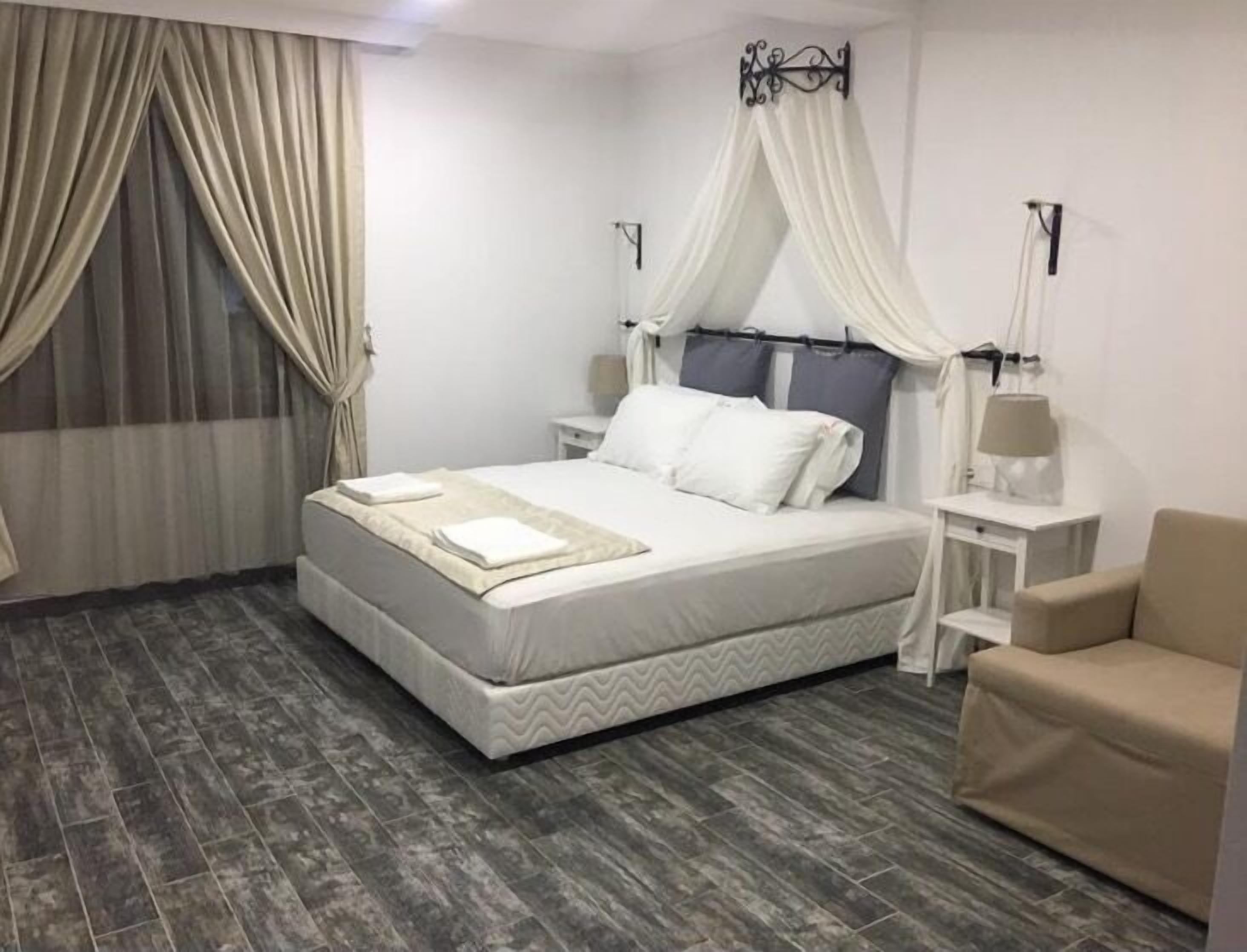 A neatly arranged bedroom with a bed, bedside tables, and a chair.