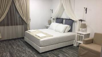 A neatly arranged bedroom with a bed, bedside tables, and a chair.