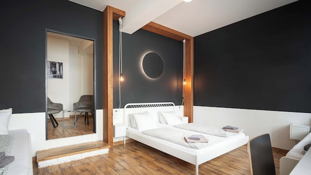 A modern bedroom with a white bed, wooden floor, and a large mirror. - Bohem Prague Hotel (Prague)