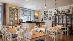 A cozy cafe with wooden tables and chairs, a brick wall, and a bookshelf filled with books. - Bohem Prague Hotel (Prague)