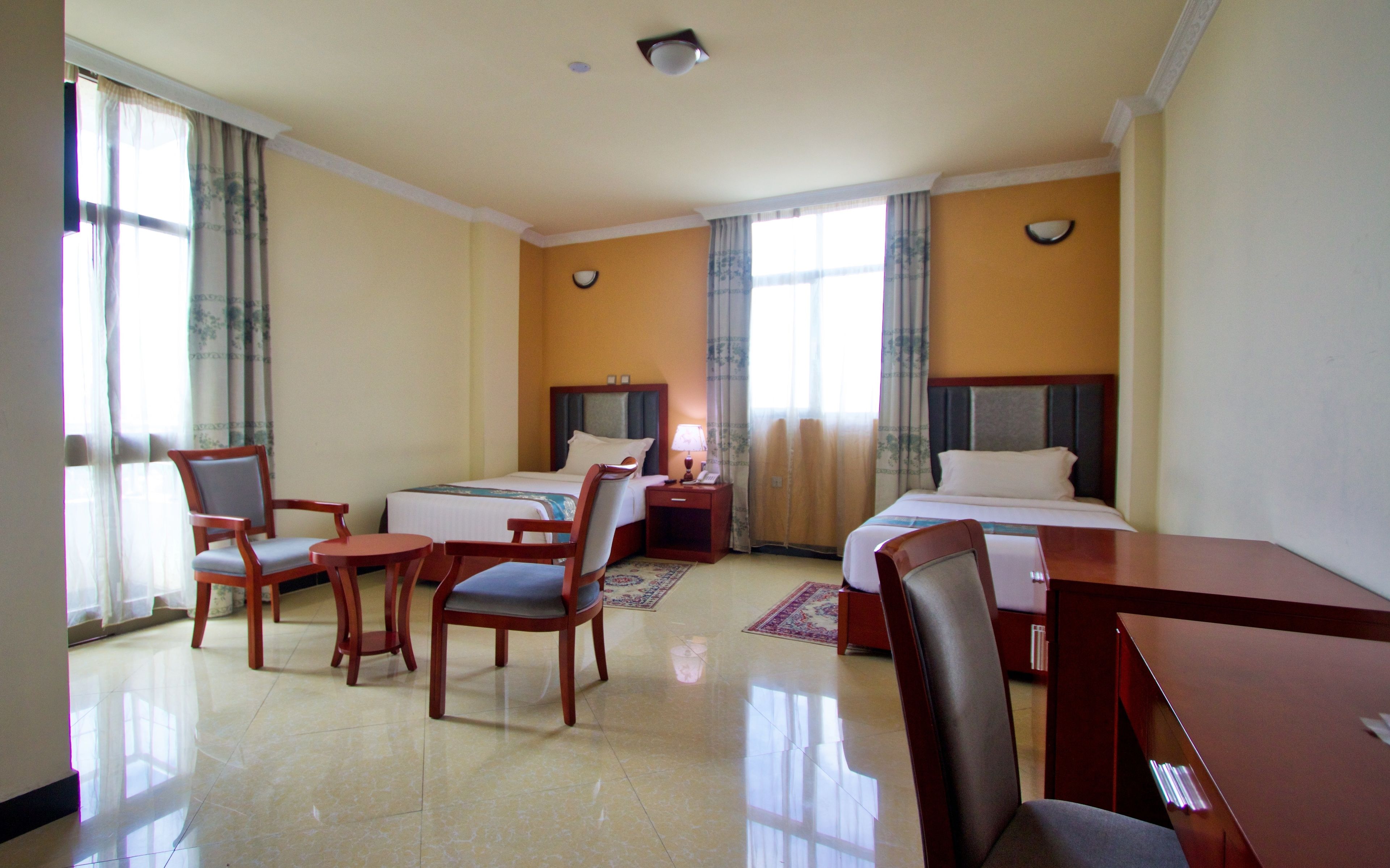 A hotel room with two beds, a desk, and two chairs.