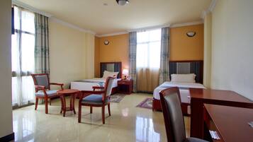 A hotel room with two beds, a desk, and two chairs.