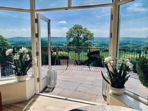 A balcony with a glass door, potted plants, and a view of a green landscape. - Shireburn Arms Hotel (Clitheroe)