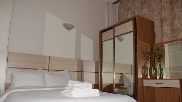 Habitación de hotel con cama, cabecero de madera, armario y espejo.
