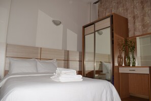 Una camera d'albergo con un letto, una testiera in legno, un armadio e uno specchio.