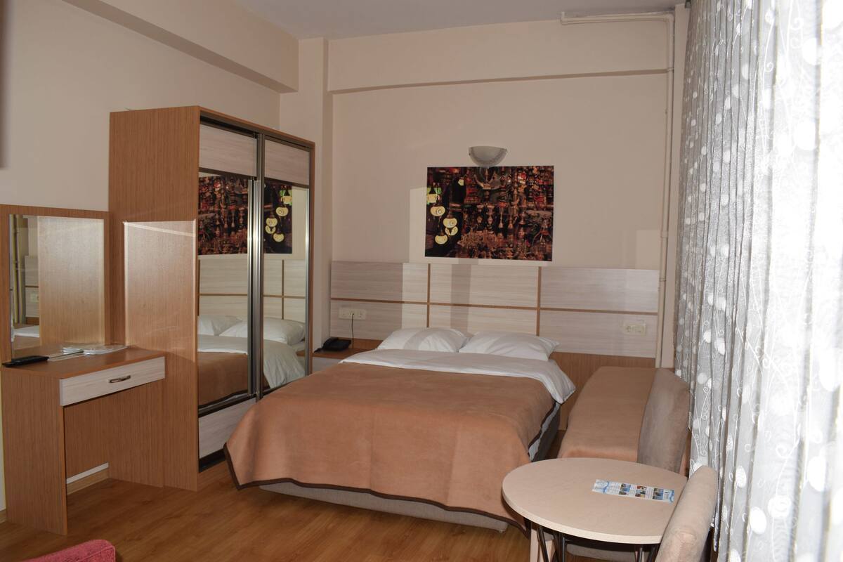 Ein Hotelzimmer mit Bett, Schreibtisch, Stuhl, Spiegel und einem Wandbild.