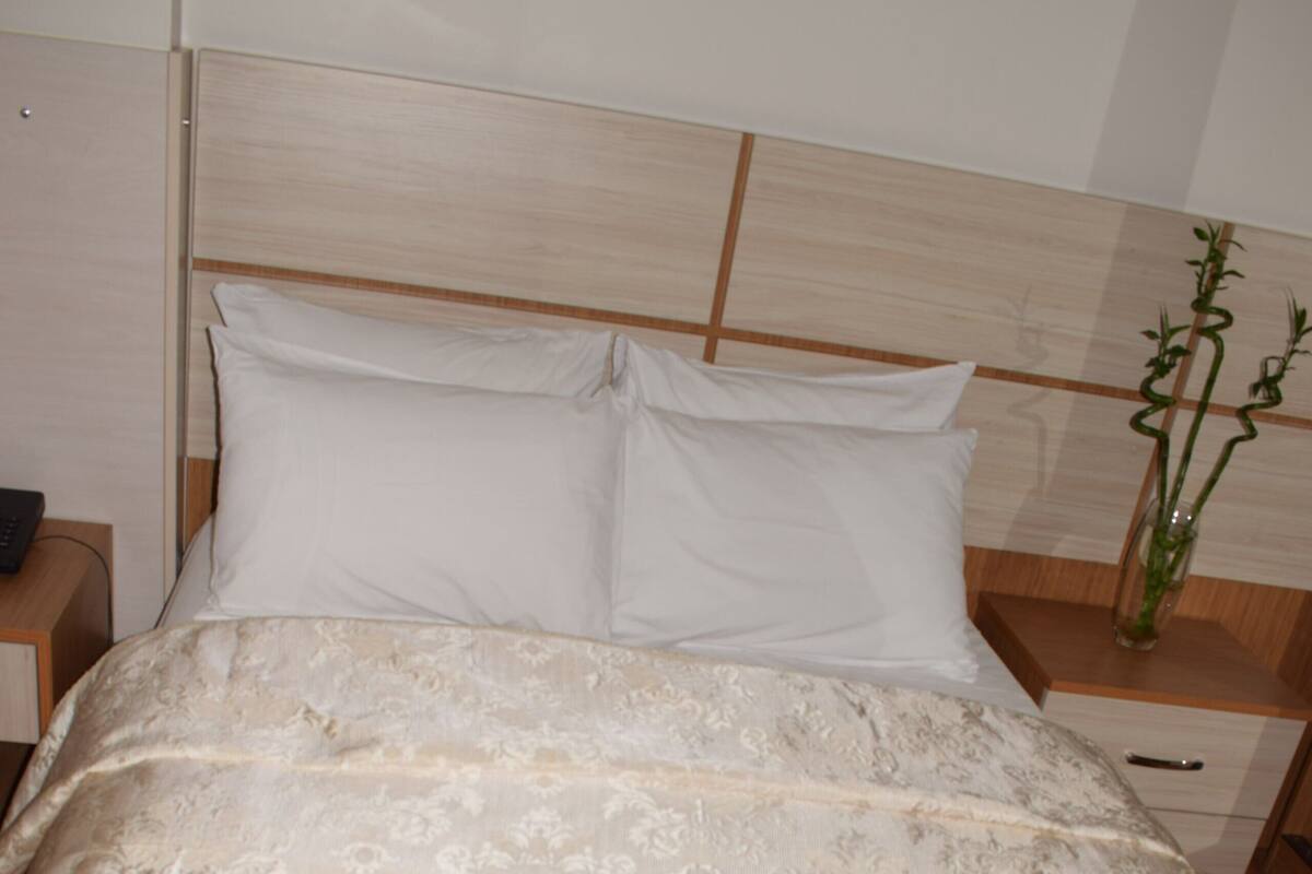 Ein ordentlich gemachtes Bett mit floraler Bettwäsche und zwei Handtüchern, die als Schwäne drapiert sind.