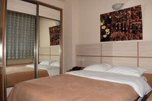 Una camera d'albergo con un letto grande, un comodino, uno specchio e un'opera d'arte appesa al muro.
